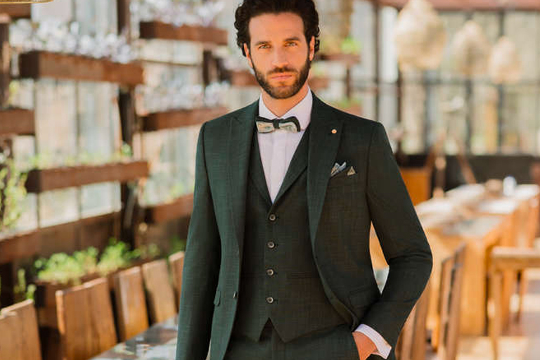 Sposo in abito verde che posa in una sala da pranzo
